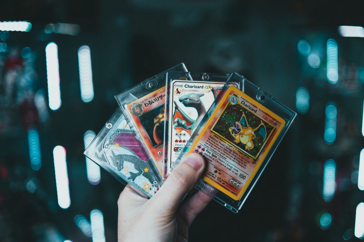A hand holding several protected trading cards in display cases